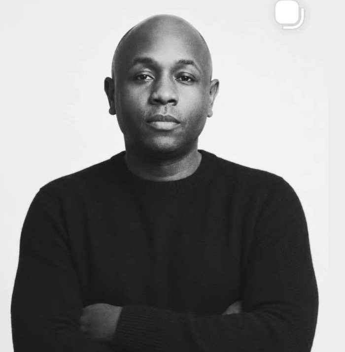 Ryan Perez in black, arms crossed, black and white studio portrait