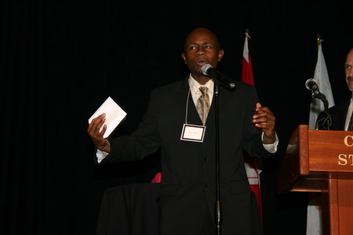Ryan Perez, wearing a "Ryan Perez" name tag, speaking at the Calgary Stampede podium